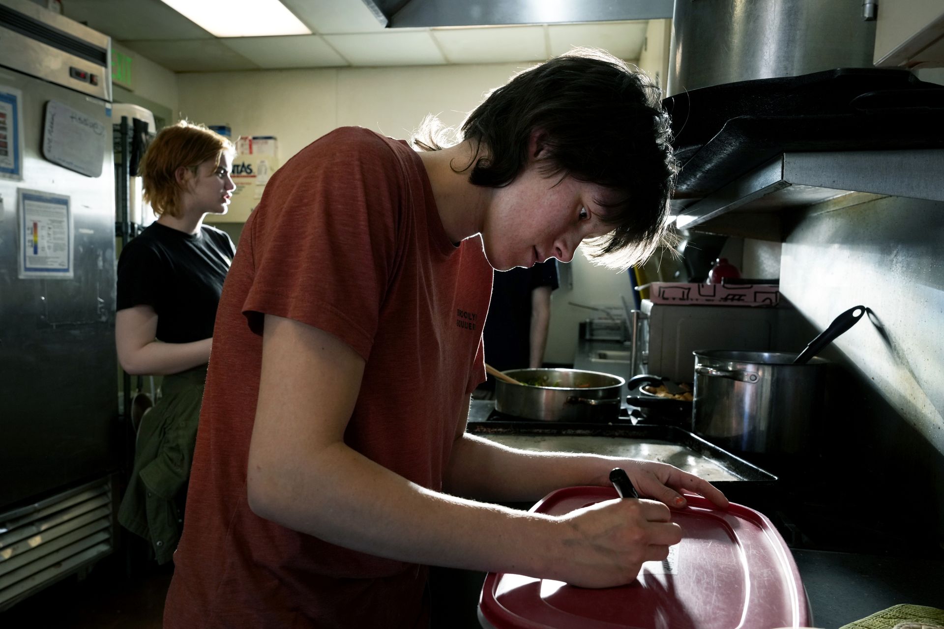 Student Melanie “Mel” Robertson helps prepare dinner and the next morning’s breakfast on April 4 at The Place, a shelter downtown for unhoused youth.