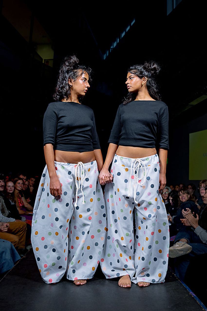 2 students modeling for the CC Fashion Show wearing matching black crop tops and wide-leg polka dot bottoms.