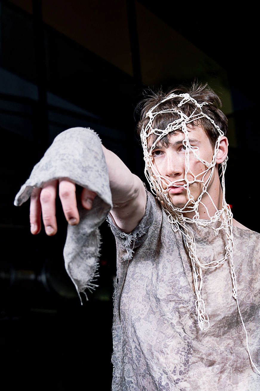 Student modeling for the CC Fashion Show wearing a grey/white distressed fabric outfit with ropes.
