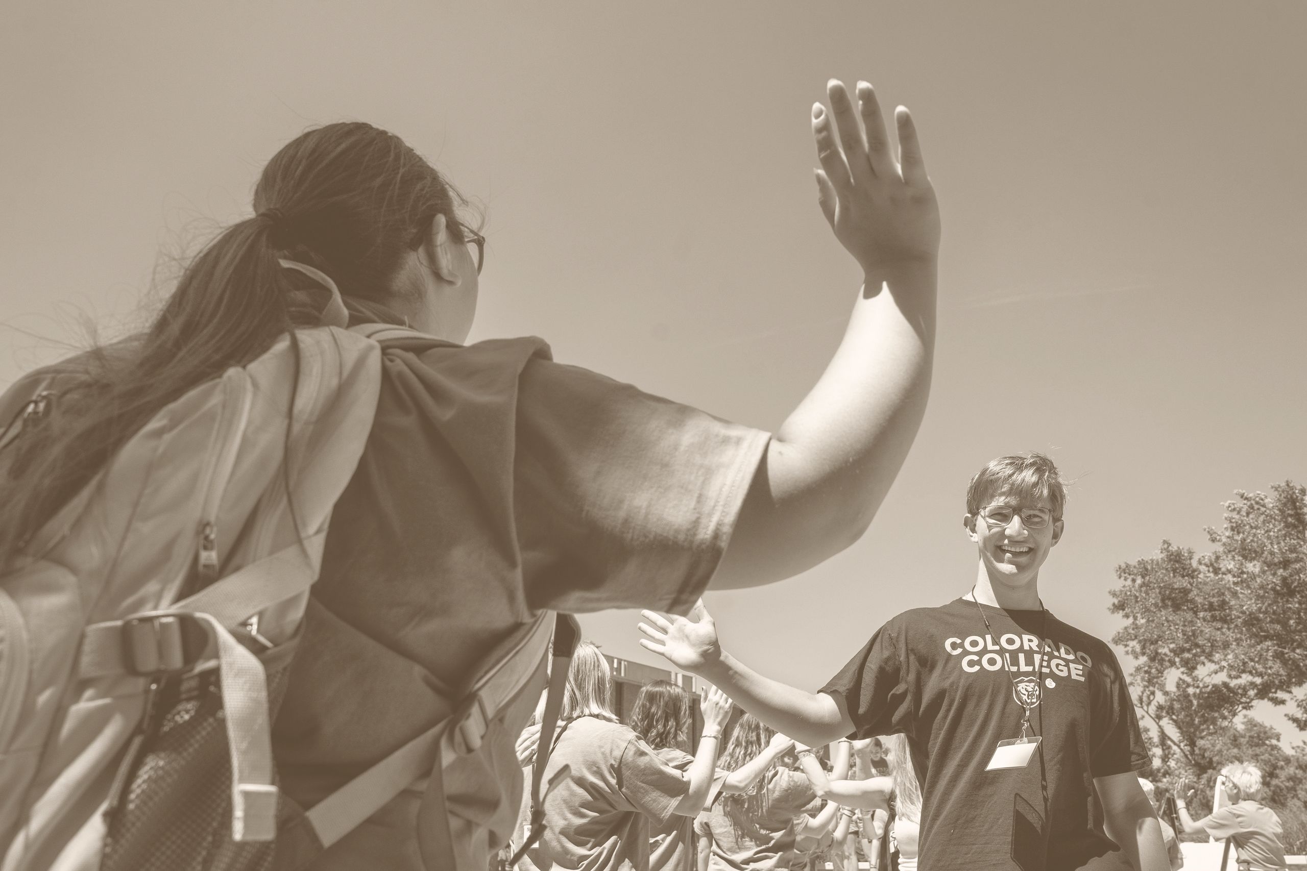 Two students going for a high-five during the College Welcome + pre-welcome spirit tunnel outside of Robson Arena.