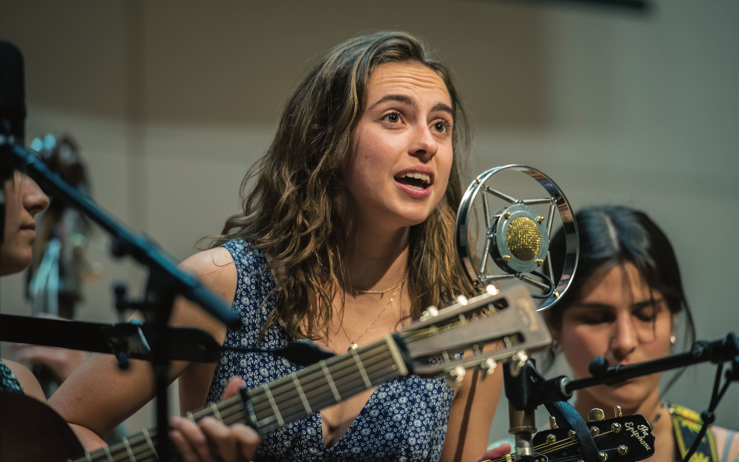 Musician singing and playing an instrument in front of a microphone