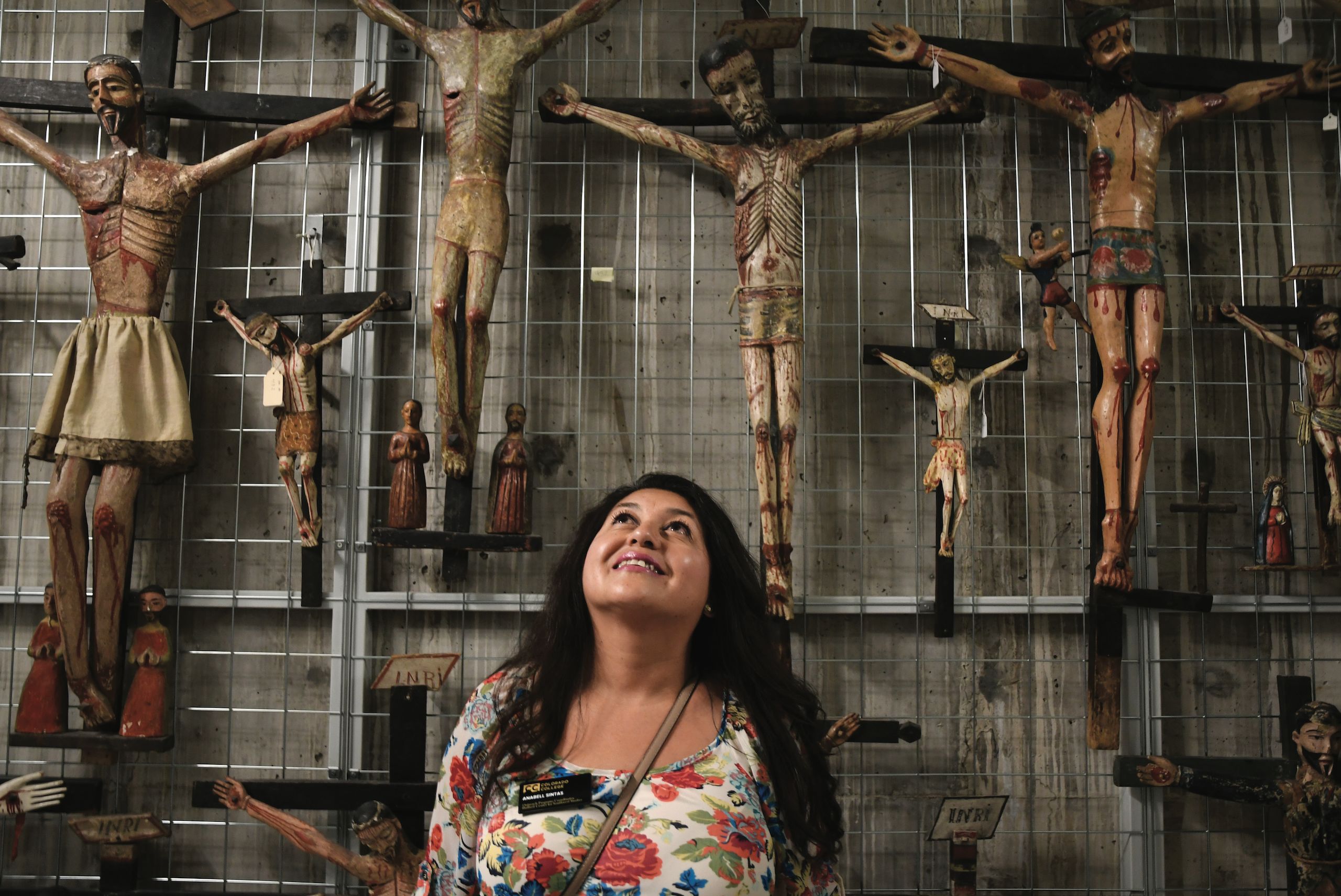Student standing in front of an Fine Arts Center exhibit of Southwestern crucifixes