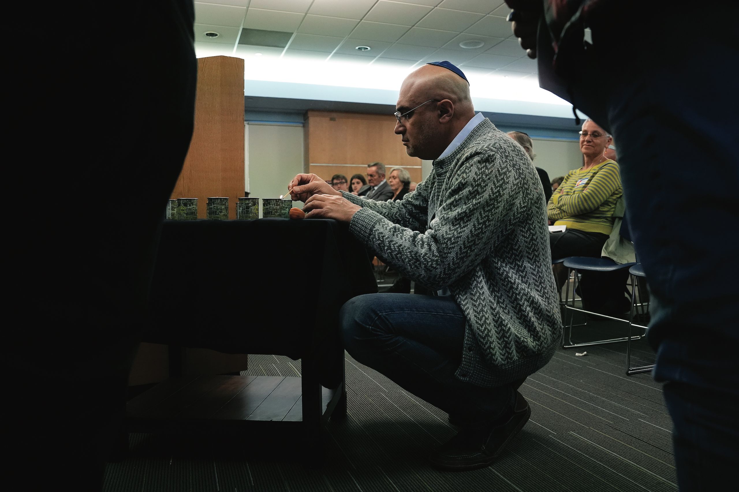 Mikhail Krasnopolskiy kneels to light a candle in memory of lives lost during the Holocaust.