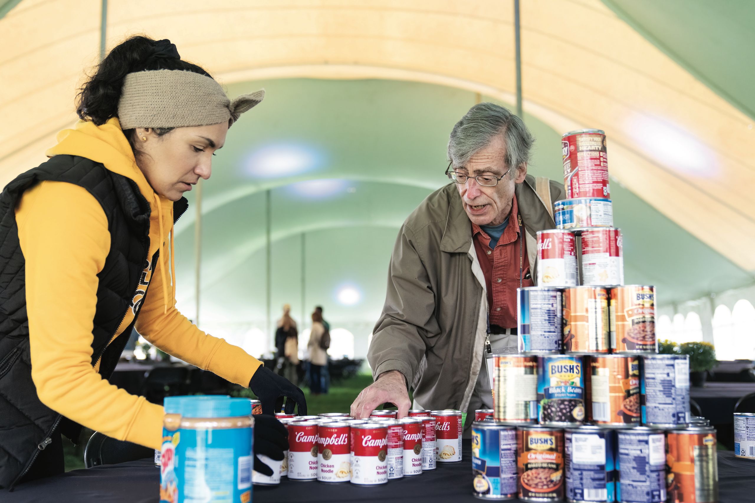 Left, Niki Sosa-Gallegos of CCE and David Makulec P'25 stack donated food at a food drive during Regional Connections family activities in Tava Tent during Homecoming and Family Weekend 2022.